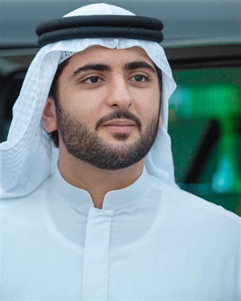 a man wearing a white outfit with a black hat on his head is looking at ...