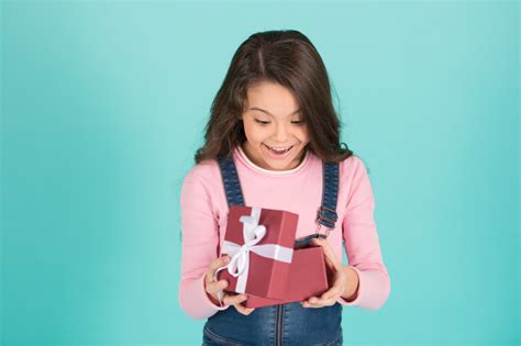 What a surprise. Child surprised excited holds gift box turquoise background. Kid girl surprised ...