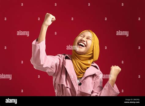 Portrait of happy success confident young teenage Asian muslim girl shows winning gesture ...