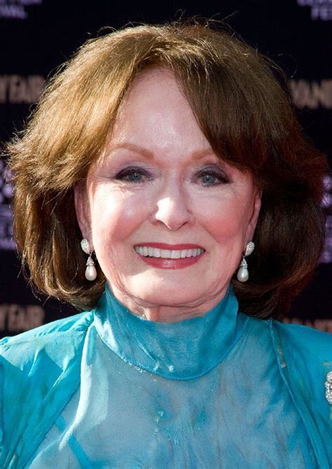 an older woman with brown hair and blue dress smiling at the camera ...