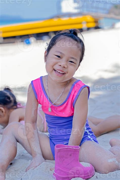 Close-up of adorable happy child girl playing with sand on ocean beach ...