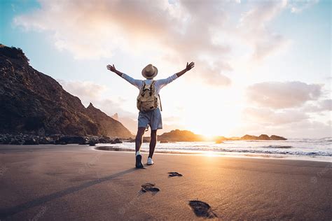 Premium . Young man arms outstretched by the sea at sunrise enjoying ...