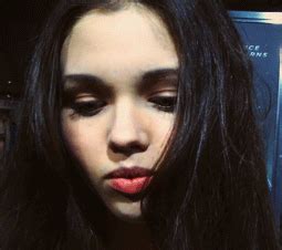 a woman with long black hair and red lipstick looks at the camera while ...