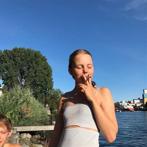 two women standing next to each other in front of a body of water, one ...