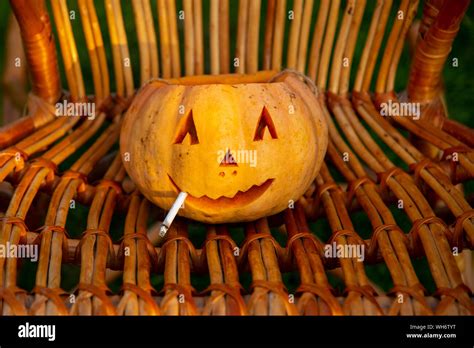 Smoking Halloween pumpkin sitting in a wicker chair Stock Photo - Alamy