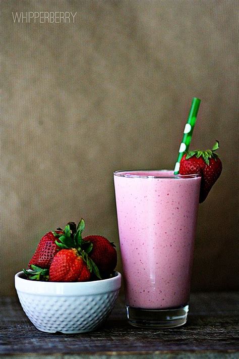 two strawberries sit next to a pink smoothie