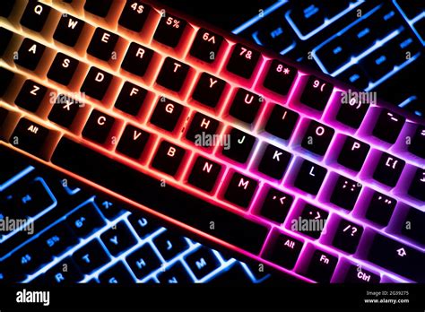 top view detail closeup of two illuminated mechanical gaming RGB keyboard on black desk on top ...