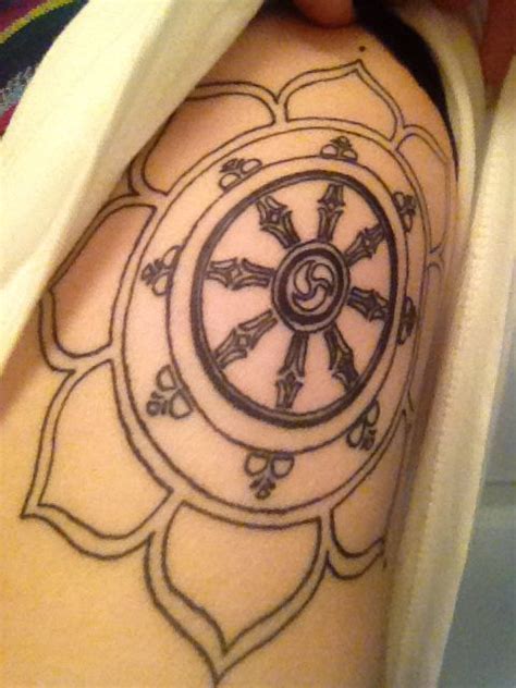 Dharma wheel in lotus flower tattoo on ribs. Symbolizes Buddhist eightfold-path. | Tattoo ...