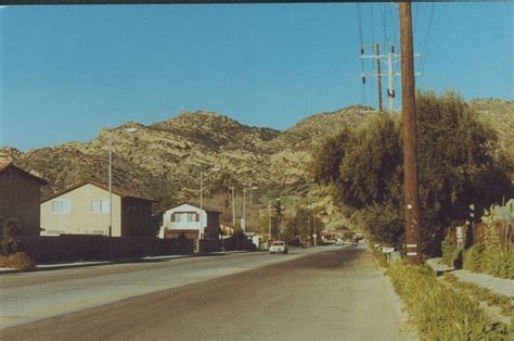 an empty street with houses and mountains in the background