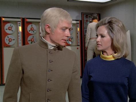 a man and woman standing next to each other in a room with records on the walls