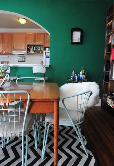 a kitchen with green walls and white chairs