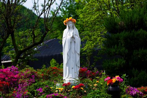 Mother Mary Sculpture with a Flower Crown in a Garden with Colorful ...