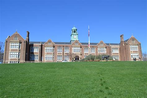 an old brick building with a clock tower on the top and green grass in front