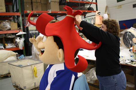 a woman standing next to a giant stuffed animal in a room filled with shelves and other items