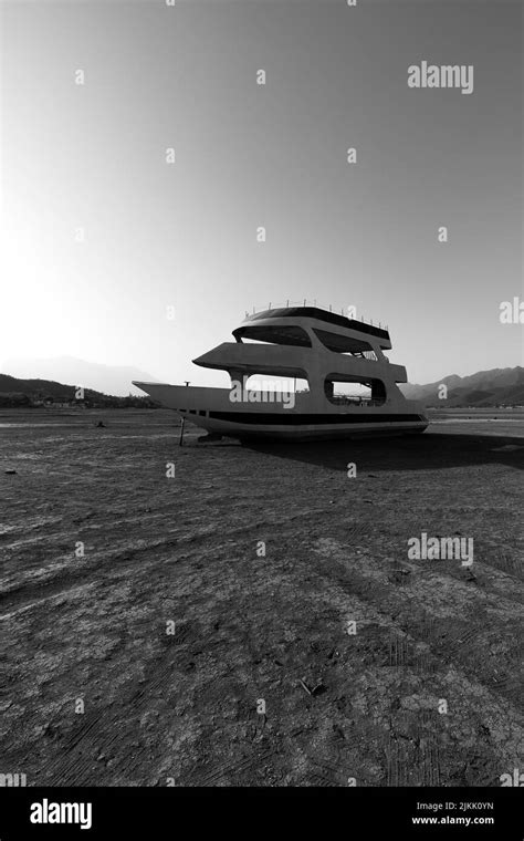 A vertical shot of an abandoned boat in a dried lake in Monterrey, Mexico shot in grayscale ...