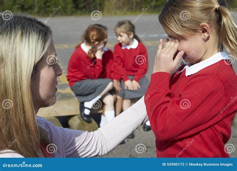 Teacher Comforting Victim Of Bullying In Playground Stock Photo - Image of caucasian, child ...