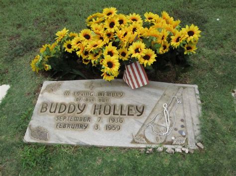 a memorial with sunflowers and an american flag in the grass next to it