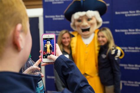 a man taking a photo with his cell phone while people look at him and smile