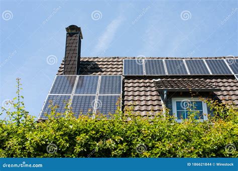 Home with Chimney and Brown Roof with Black Rectangular Solar Panels ...