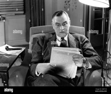 1930s 1940s OLDER BUSINESSMAN SITTING IN CHAIR READING NEWSPAPER Stock Photo - Alamy