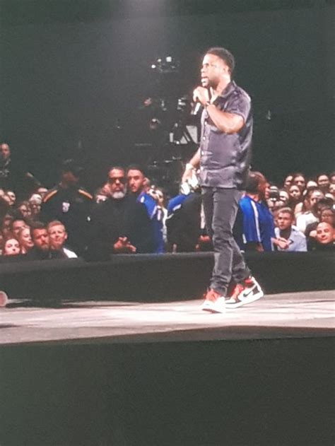 a man standing on top of a stage holding a microphone in front of a crowd