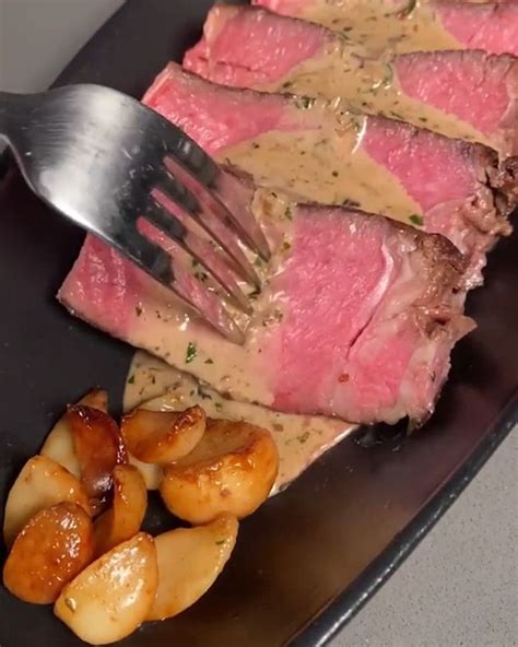 a plate with steak, potatoes and gravy on it next to a fork