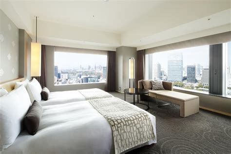 a hotel room with two large beds and a view of the city from it's windows