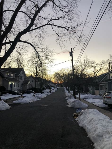 a street with snow on the ground and houses in the background