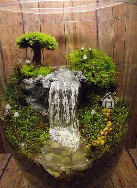 an aquarium with moss, rocks and water flowing from the top to the bottom in front of a wooden wall