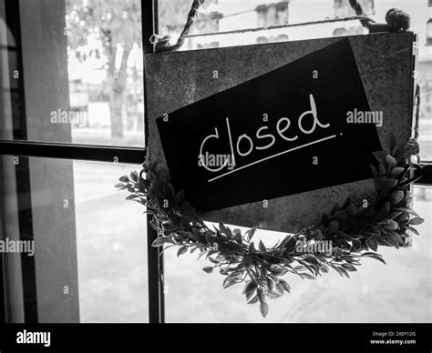 Shop closed, black notice sign with words "CLOSED !" hanging on glass door in front of the ...