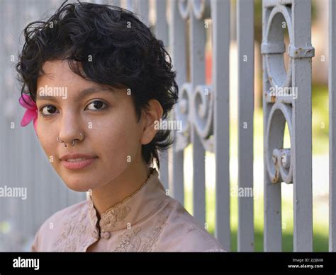 Young pretty sensual Latina woman with big brown eyes and a flower in her short curly black hair ...