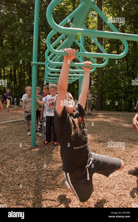 Child playing on a overhead ladder swing in a school playground Stock Photo - Alamy