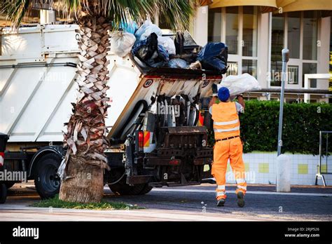 garbage collector loads garbage on the truck Stock Photo - Alamy