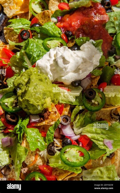 Loaded toppings beef nachos with guacamole sour cream and tomato salsa Stock Photo - Alamy