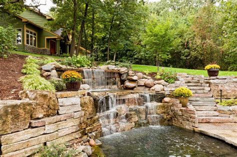 A house on a hillside features a rolling waterfall beside the stone ...