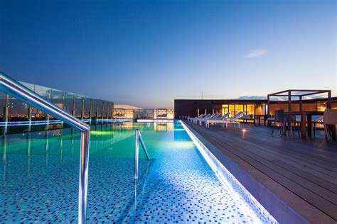 an outdoor swimming pool at dusk with lounge chairs and tables on the ...