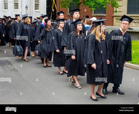 Wearing graduation caps and gowns, multiracial Harvard University graduates form a procession in ...