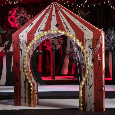 a red and white circus tent with lights on it's sides in the middle of a stage