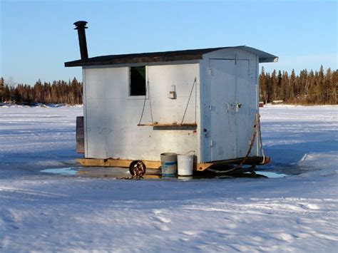 a white outhouse sitting in the middle of a snow covered field