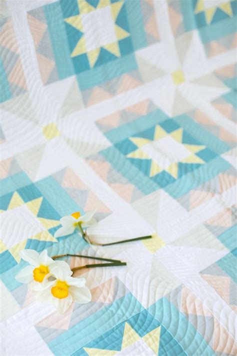 scissors are laying on the edge of a blue and white quilt with yellow flowers in it