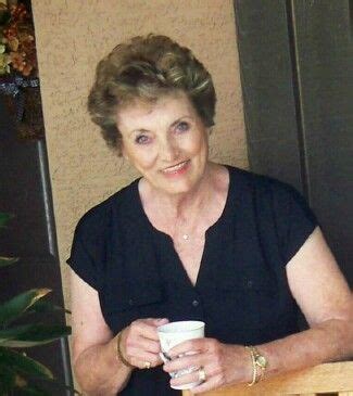 an older woman sitting at a table holding a coffee cup
