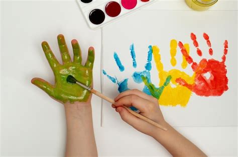 Premium Photo | The child draws his hand with green paint and a brush Finger painting or art ...