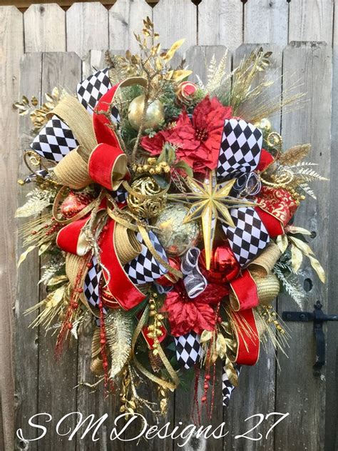 a christmas wreath hanging on the side of a wooden fence with red ...