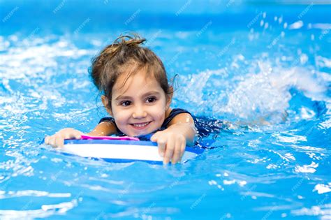 Premium Photo | Little girl learning to swim in the pool