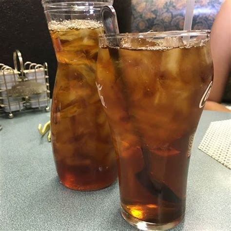 two glasses filled with ice tea sitting on top of a table