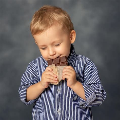 Premium Photo | Portrait of small boy kid eating chocolate on grey ...