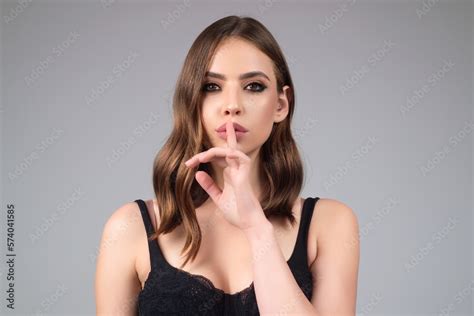 Girl showing shhh sign with finger near lips, standing over studio ...