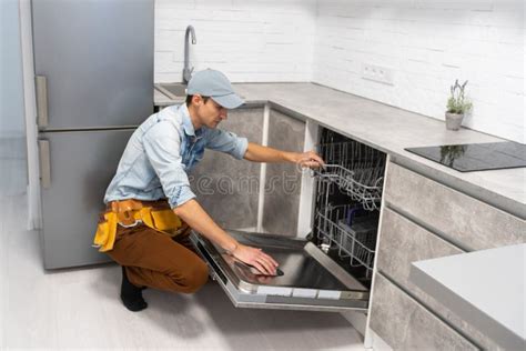 Process of Dishwashing Machine Installation. Young Service Man Setting Up Dishwasher in New ...