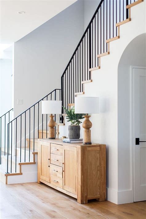 Modern farmhouse foyer features a custom staircase with wrought iron ...