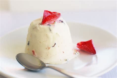 a small dessert with strawberries on top is sitting on a plate next to a spoon